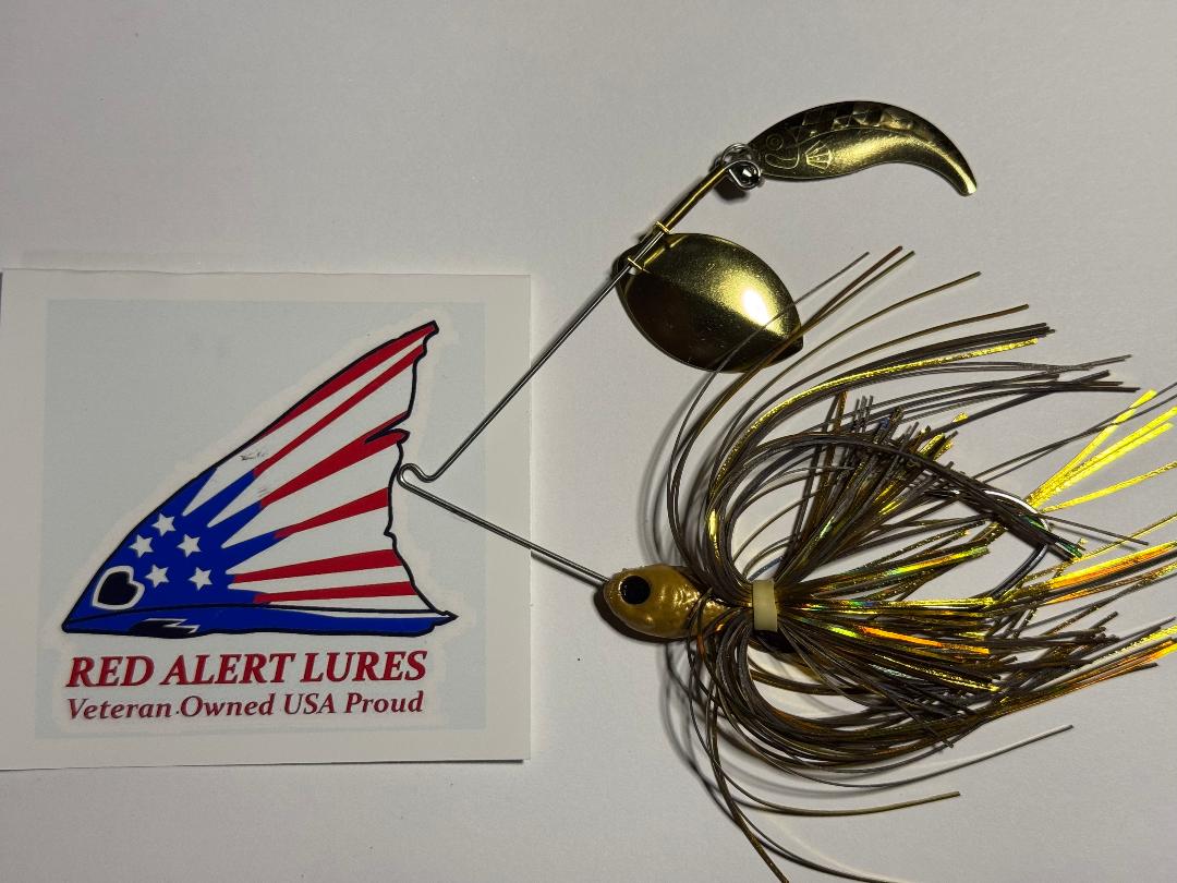 A hand-made spinnerbait fishing lure with a golden blade and black and yellow feathers next to a red, white, and blue American flag-themed business card.